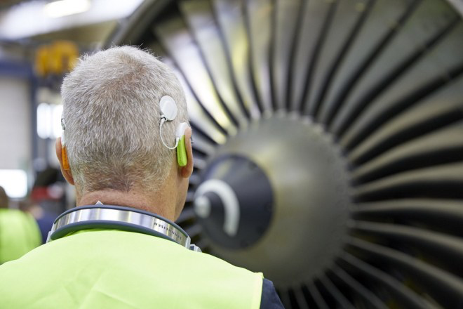 Foto eines Teilnehmers vor einer Antriebsdüse des Flugzeugs, das Implantat ist gut sichtbar